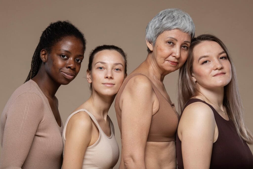 Cuatro mujeres con diferentes tonos y tipos de piel posando juntas.